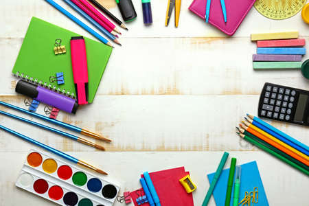 Frame made of school supplies on white wooden background
