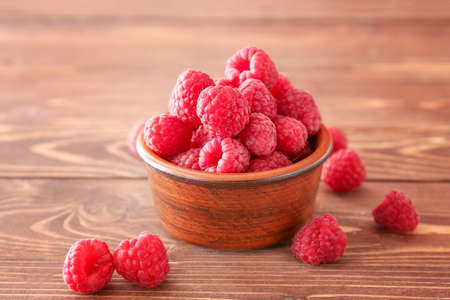 Bowl with fresh raspberries on wooden table
