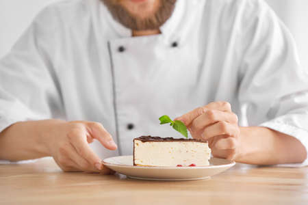 Handsome male chef with tasty cake in kitchenの写真素材
