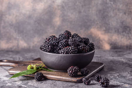 Bowl with tasty blackberries on grunge background