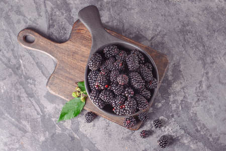 Bowl with tasty blackberries on grunge background