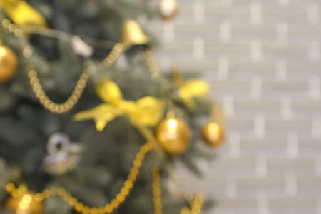Beautifully decorated Christmas tree near brick wall, blurred view