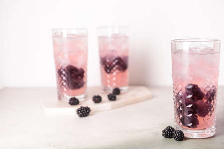 Glasses of tasty blackberry lemonade on table