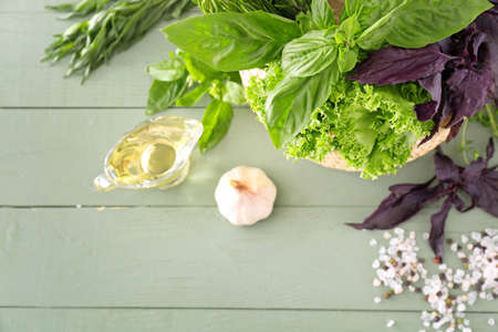 Different fresh herbs with spices, oil and garlic on wooden table