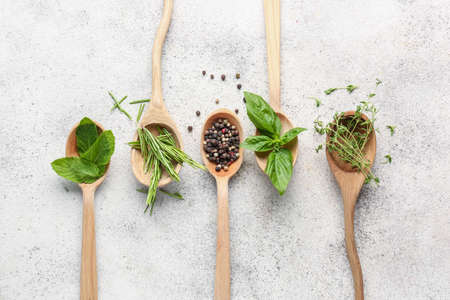 Spoons with different fresh herbs and spices on light backgroundの写真素材