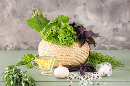 Different fresh herbs with spices, oil and garlic on wooden tableの写真素材