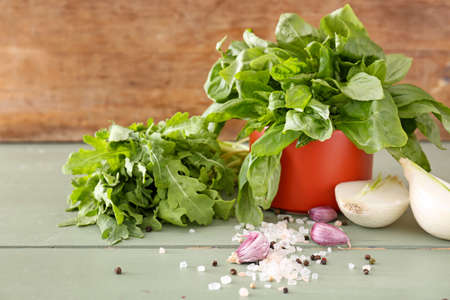 Different fresh herbs with vegetables and spices on wooden tableの写真素材