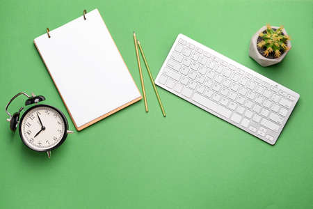 Modern computer keyboard with stationery and alarm clock on color backgroundの写真素材