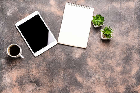 Modern tablet computer with notebook and cup of coffee on gray backgroundの写真素材