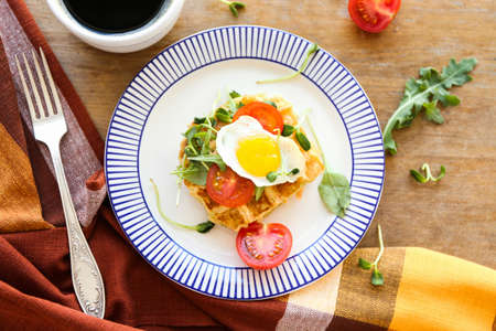 Plate with tasty waffles and fried egg on wooden tableの写真素材