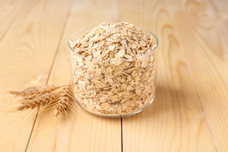 Container with raw oatmeal on wooden table