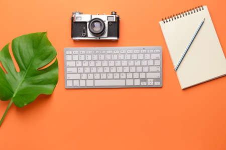 Modern computer keyboard with stationery and retro photo camera on color backgroundの写真素材