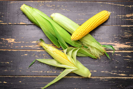 Fresh corn cobs on wooden background