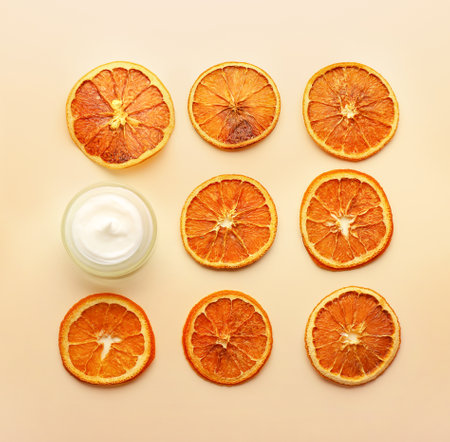Jar of natural cream and dry orange slices on light backgroundの写真素材