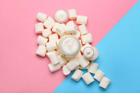 Jars of natural cream and marshmallows on color backgroundの写真素材