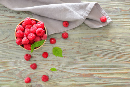 Bowl with tasty ripe raspberries on wooden table