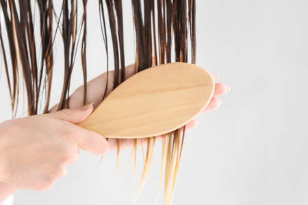 Beautiful young woman brushing hair after washing at home, closeupの写真素材