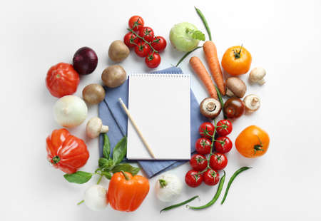 Different fresh vegetables with notebook on white backgroundの写真素材