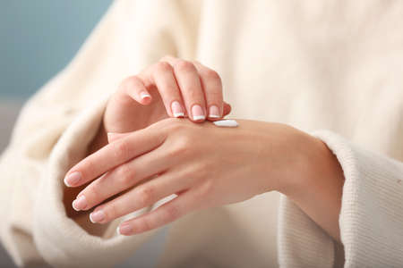 Young woman applying natural cream onto skin at home