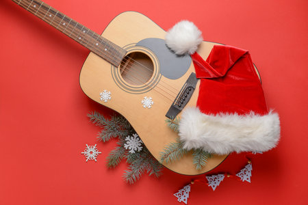 Guitar with Santa hat and Christmas decor on color backgroundの写真素材