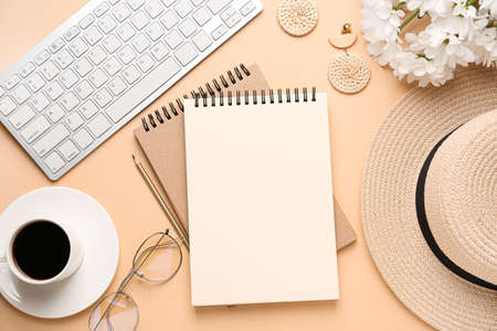Computer keyboard with notebooks, cup of coffee and female accessories on color backgroundの写真素材