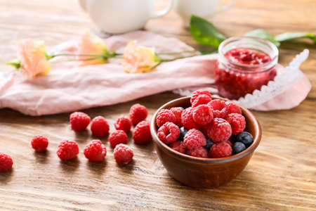 Bowl with tasty ripe berries on wooden tableの写真素材