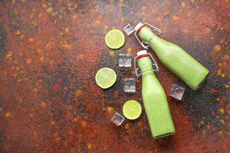 Bottles of fresh healthy smoothie, sliced citrus fruits and ice cubes on grunge backgroundの写真素材