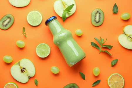 Bottle of fresh healthy smoothie and ingredients on color backgroundの写真素材