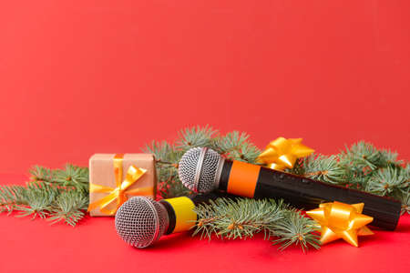 Modern microphones with Christmas decor on color background