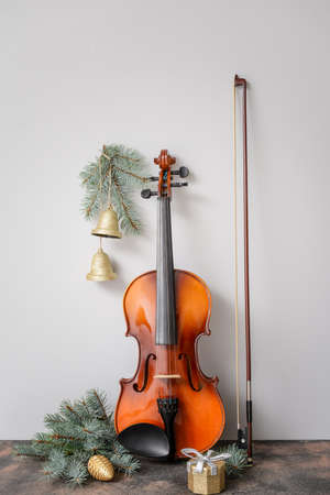 Violin and Christmas decor on table against light background