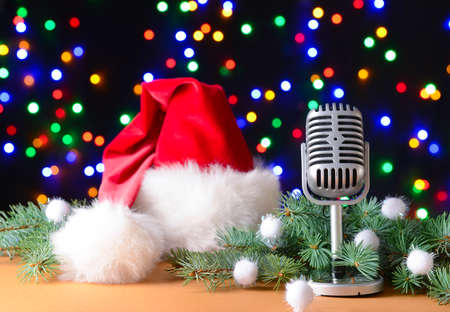 Retro microphone with Santa Claus hat on table against defocused lightsの写真素材
