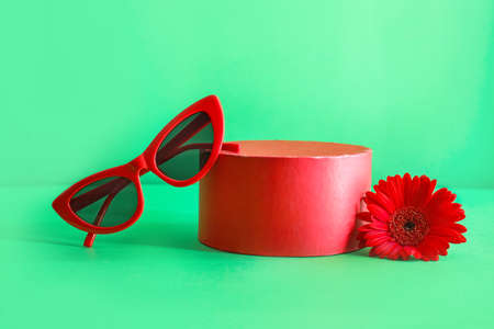 Box with stylish sunglasses and flower on color backgroundの写真素材