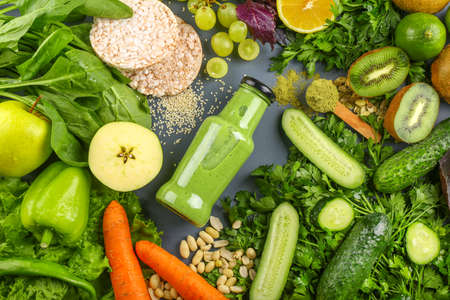 Bottle of tasty green smoothie with ingredients on gray backgroundの写真素材