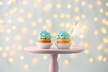 Tasty Birthday cupcakes on stand against defocused lightsの写真素材