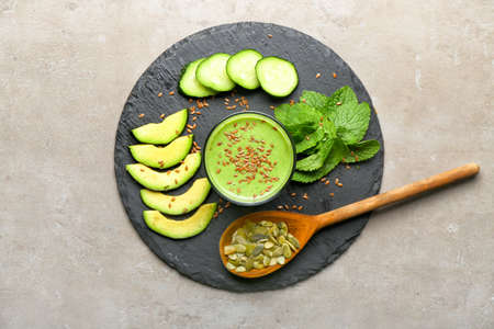 Glass of healthy smoothie with ingredients on gray background