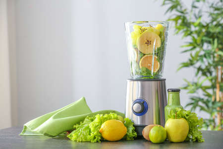 Blender with ingredients for healthy smoothie on table in kitchenの写真素材