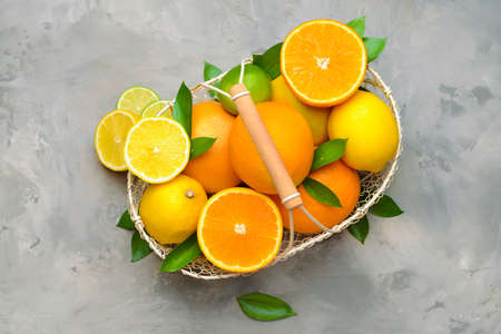 Basket with different citrus fruits on grunge background