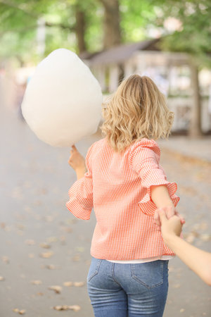 Woman with sweet cotton candy outdoors, back viewの写真素材