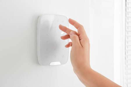 Woman entering code on panel of modern security system