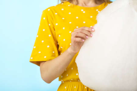 Young woman with tasty cotton candy on color background, closeupの写真素材