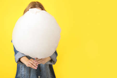 Young woman with tasty cotton candy on color background