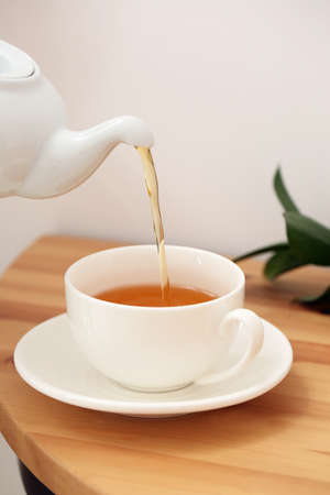 Pouring of hot tea in cup on tableの写真素材