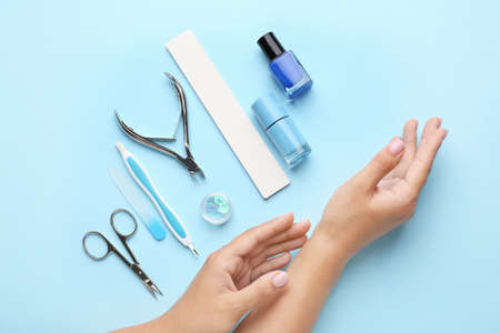 Female hands with supplies for manicure on color backgroundの写真素材