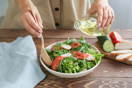 Woman preparing tasty arugula salad on table closeupの写真素材