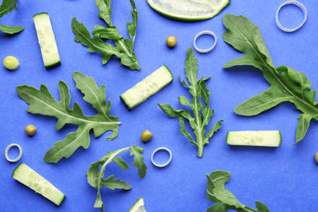 Fresh arugula with vegetables on color background