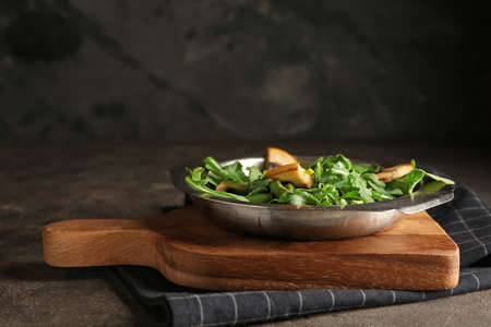 Plate with tasty arugula salad on table