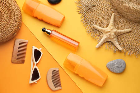 Beach accessories and sun protection cream on color background
