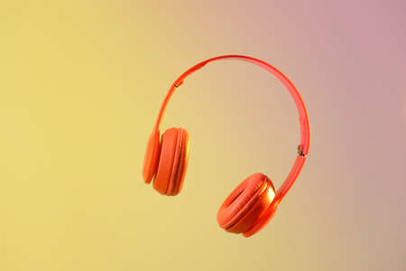 Modern headphones on color background