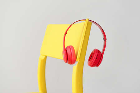 Modern headphones on chair against light background
