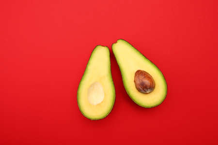 Halves of ripe avocado on color background